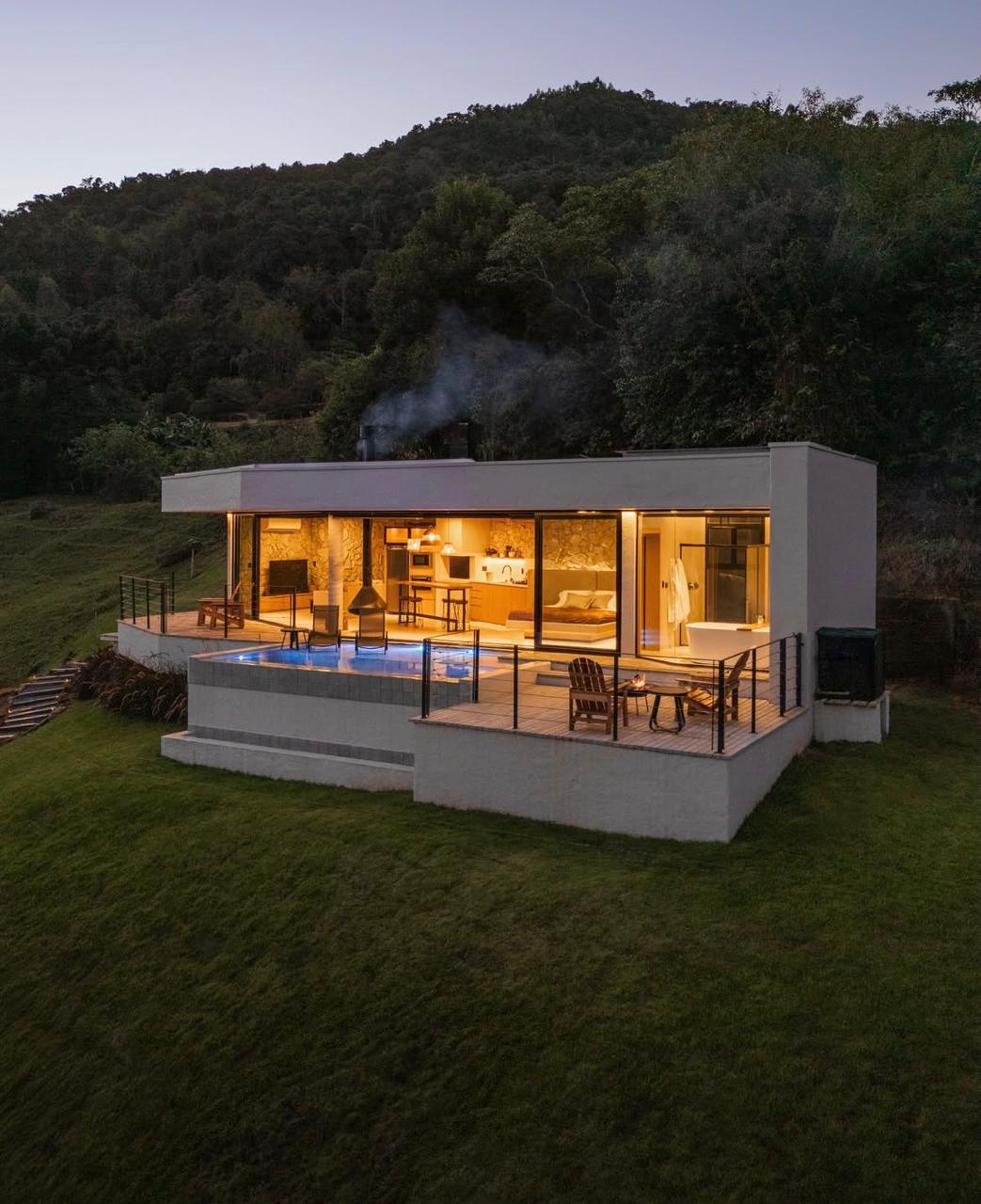 Casa moderna com piscina e iluminação acolhedora em meio à natureza